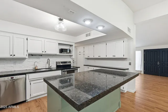 a kitchen with stainless steel appliances granite countertop a sink stove and cabinets