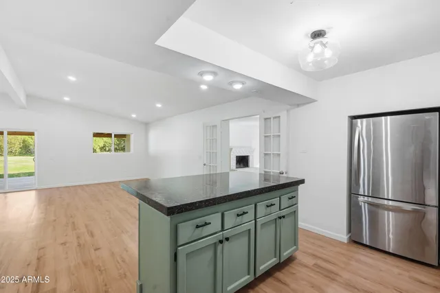 a kitchen with stainless steel appliances granite countertop a refrigerator a sink a stove and white cabinets with wooden floor