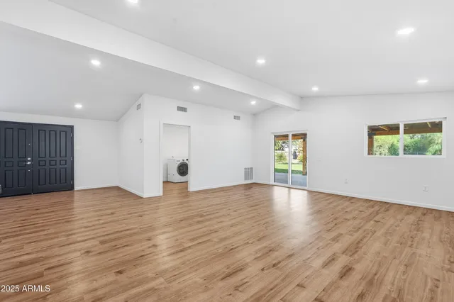 a view of an empty room with wooden floor and windows
