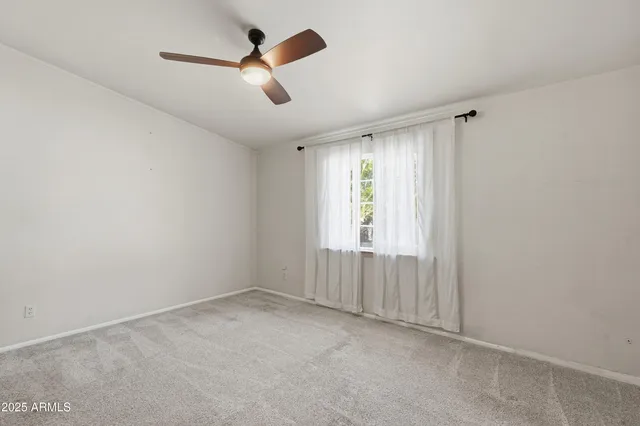 an empty room with ceiling fan and windows