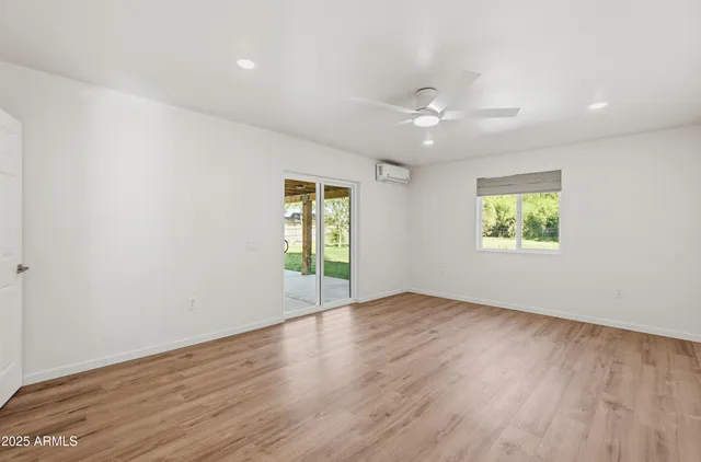 an empty room with wooden floor chandelier fan and windows