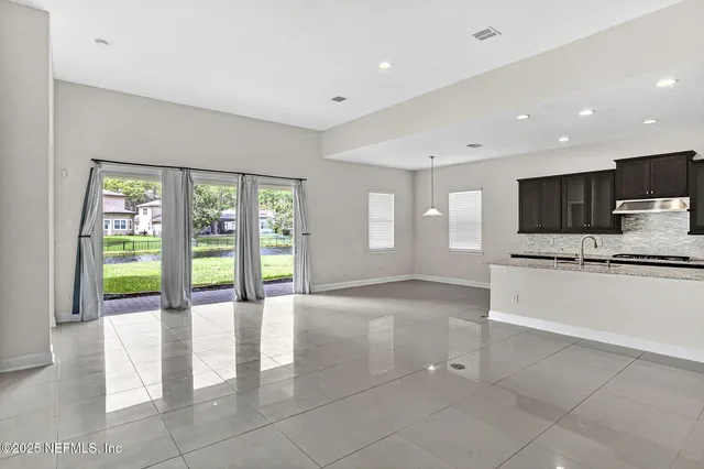 a view of an empty room with a kitchen view and a window