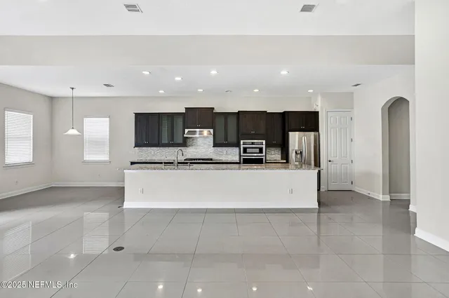 a large white kitchen with stainless steel appliances kitchen island granite countertop a large counter top and a stove