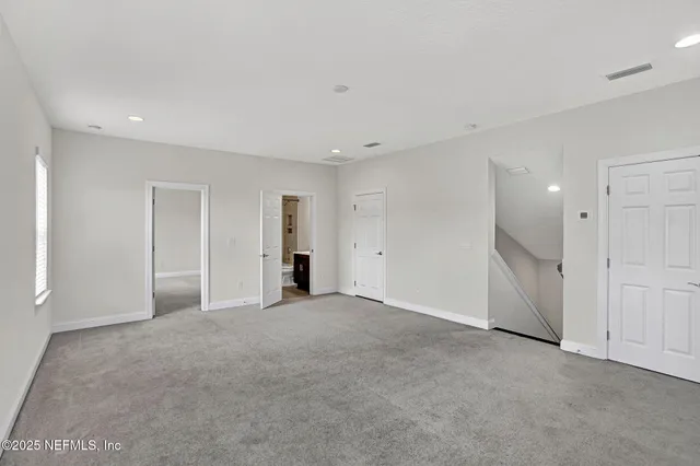 a view of an empty room with closet and entryway