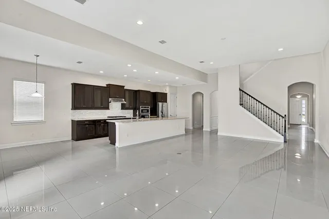 a large white kitchen with stainless steel appliances kitchen island a sink dishwasher a stove and a refrigerator with wooden floor