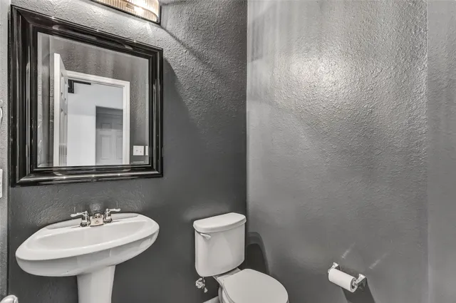a bathroom with a toilet sink and mirror