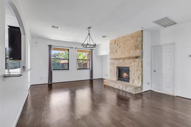 an empty room with wooden floor a fireplace and windows