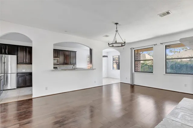 an empty room with wooden floor chandelier and windows