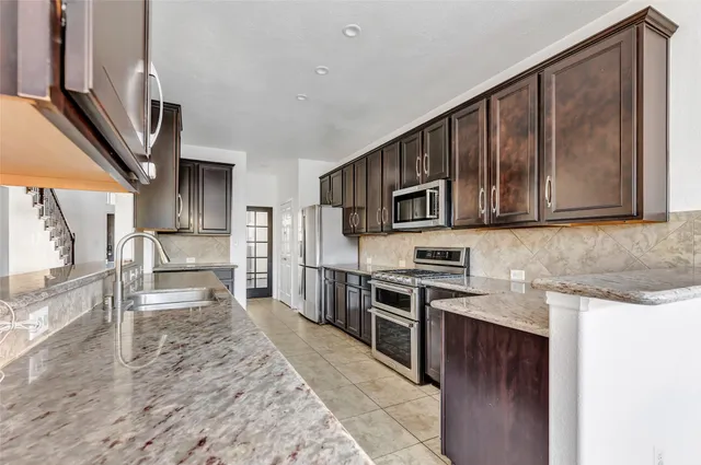 a kitchen with stainless steel appliances granite countertop a stove top oven a sink and dishwasher