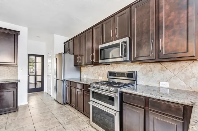 a kitchen with granite countertop a refrigerator stove and microwave