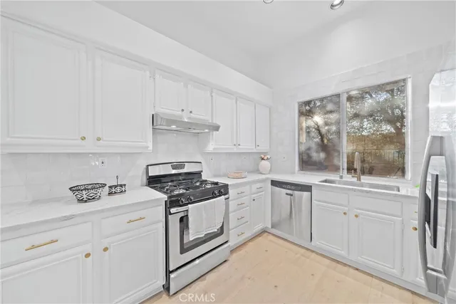 a kitchen with a refrigerator a stove a sink and a dining table with wooden floor