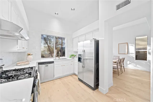 a kitchen with stainless steel appliances kitchen island granite countertop a refrigerator and a stove top oven