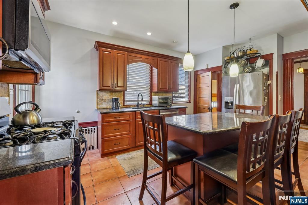133 Hudson Avenue Ridgefield Park, NJ 07660 - Photo 4 of 14 a kitchen with stainless steel appliances granite countertop a stove a sink dishwasher a dining table and chairs with wooden floor