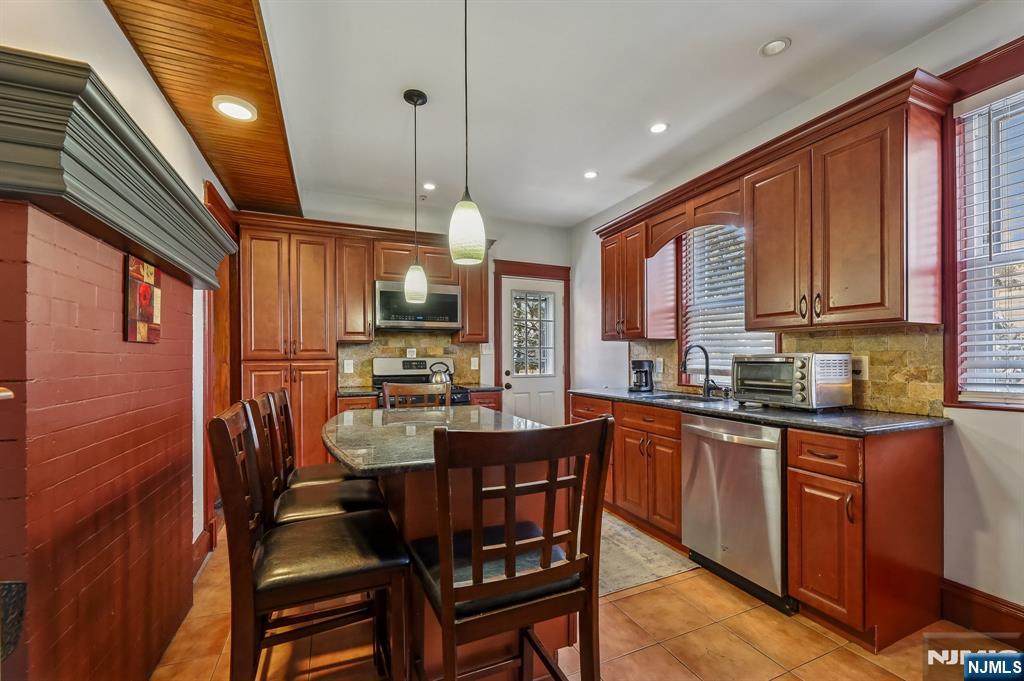 133 Hudson Avenue Ridgefield Park, NJ 07660 - Photo 5 of 14 a kitchen with stainless steel appliances granite countertop a refrigerator a sink dishwasher a dining table and chairs with wooden floor