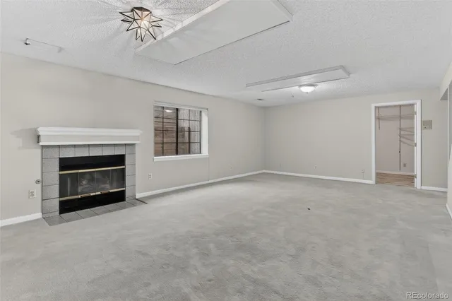 an empty room with fireplace cabinet and windows