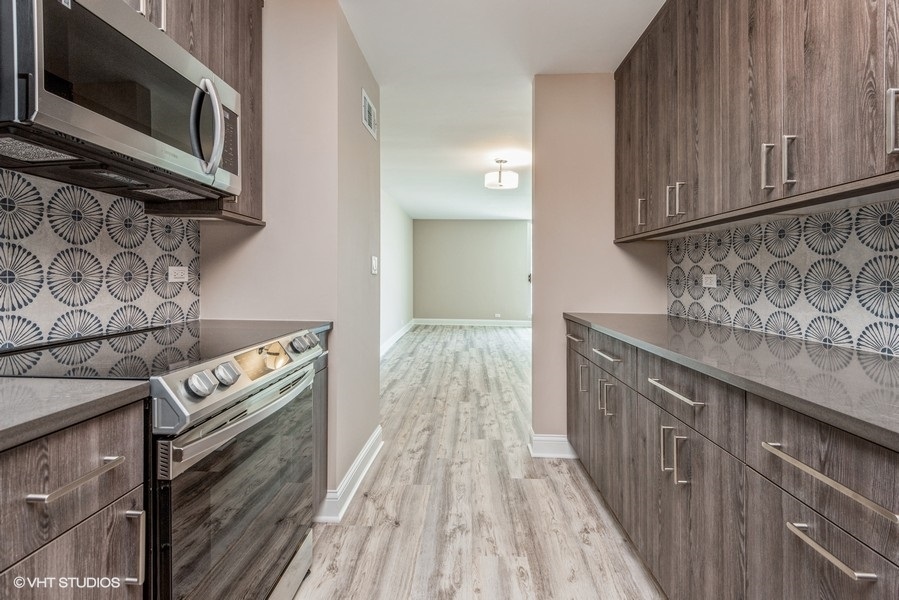 6033 North Sheridan Road, Unit 31E Chicago, IL 60660 - Photo 8 of 15 a kitchen with stainless steel appliances granite countertop a stove and a microwave