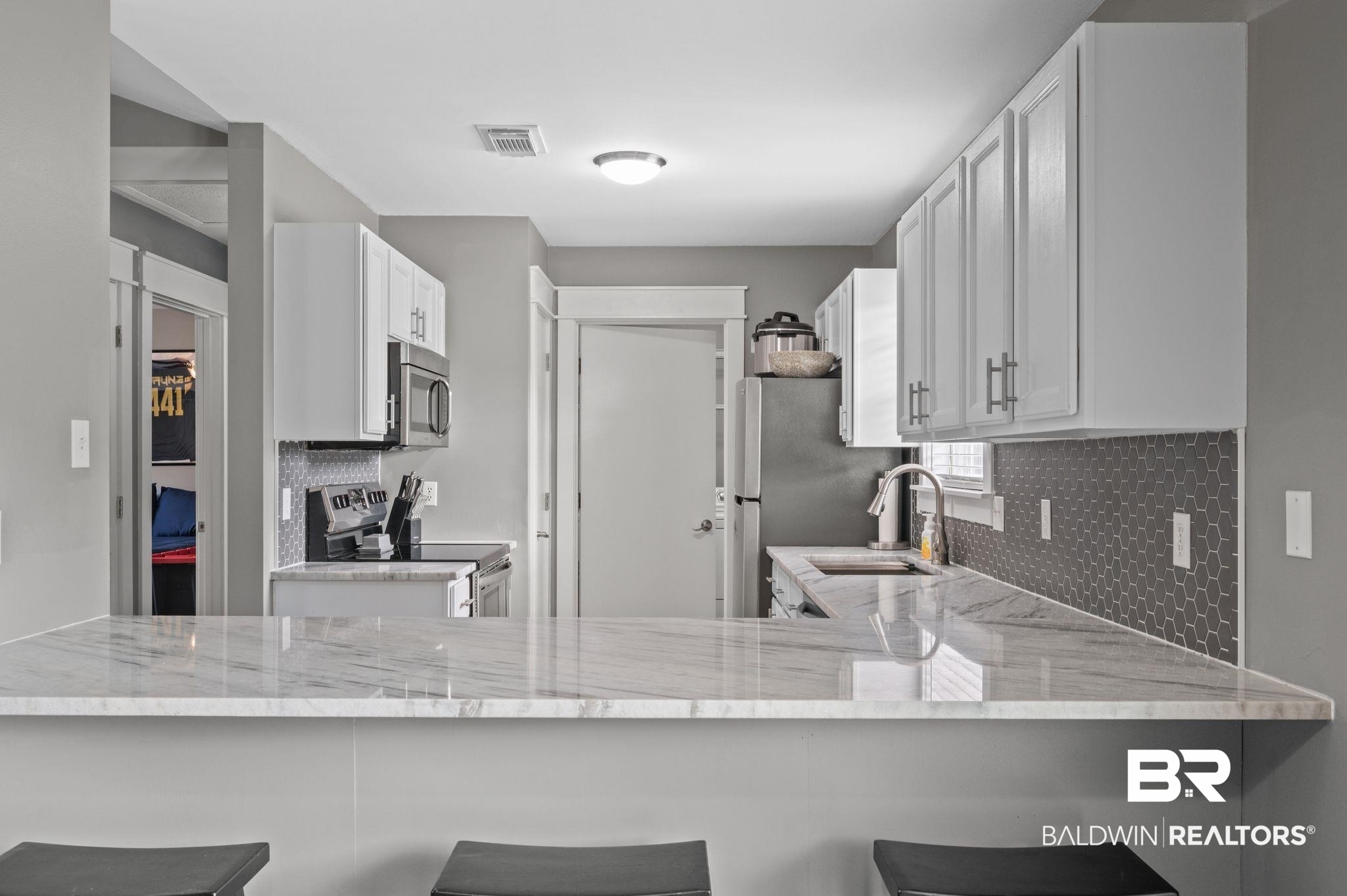 1107 North Oak Street Loxley, AL 36551 - Photo 7 of 40 Kitchen featuring a kitchen bar, stainless steel appliances, sink, kitchen peninsula, and white cabinets