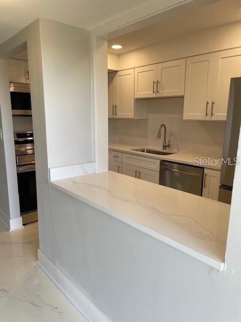 1 Boca Ciega Point Boulevard, Unit 115 St. Petersburg, FL 33708 - Photo 5 of 35 a kitchen with stainless steel appliances a sink stove and cabinets