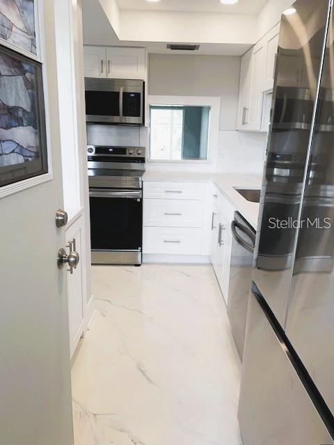 1 Boca Ciega Point Boulevard, Unit 115 St. Petersburg, FL 33708 - Photo 9 of 35 a kitchen with stainless steel appliances a stove sink and microwave