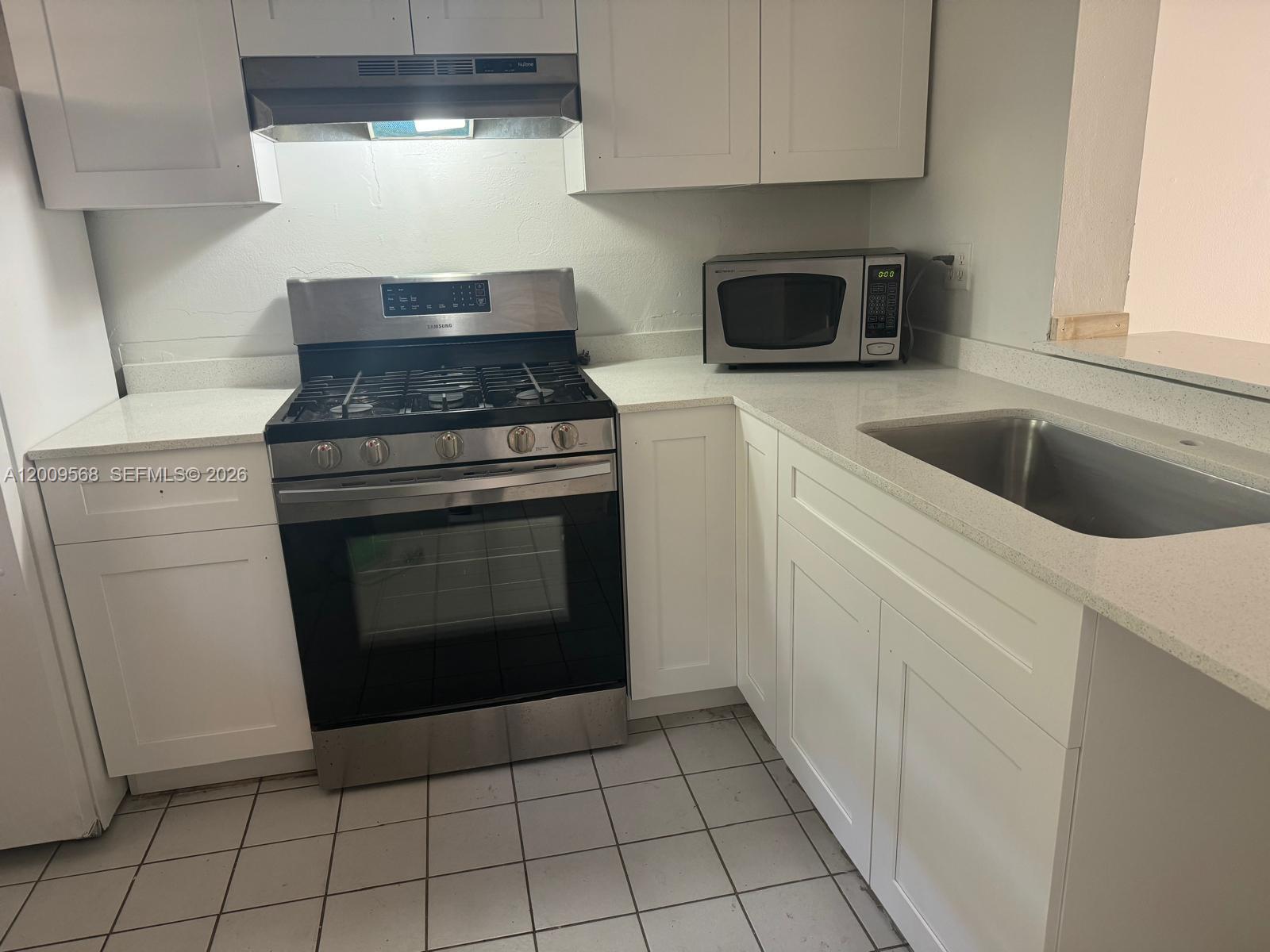 18111 Northwest 68th Avenue, Unit F106 Hialeah, FL 33015 - Photo 5 of 10 a stove top oven sitting inside of a kitchen
