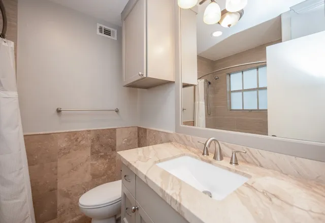 a bathroom with a granite countertop sink a toilet and a mirror
