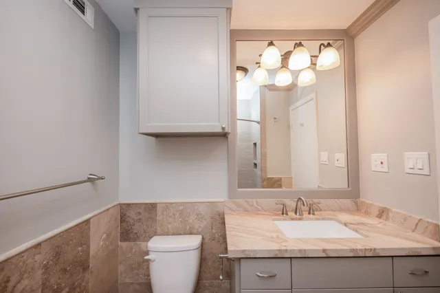 a bathroom with a granite countertop sink mirror and a toilet