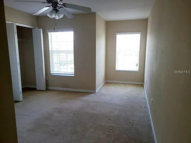 an empty room with a window and a chandelier fan