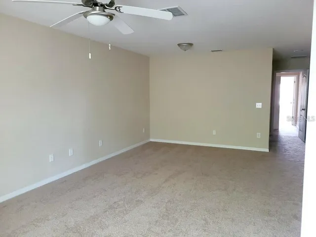 an empty room with a ceiling fan and carpet