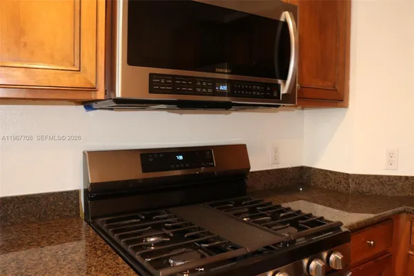 a kitchen with granite countertop a refrigerator and a stove top oven