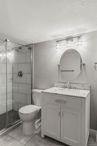 a bathroom with a toilet sink vanity granite and shower