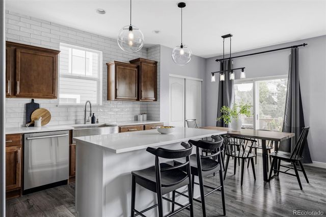 a kitchen with stainless steel appliances granite countertop a dining table chairs sink and wooden floor