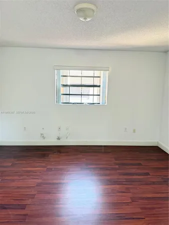 an empty room with wooden floor and window