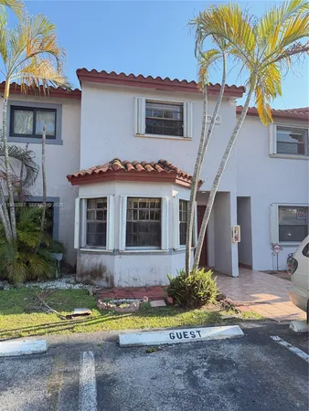 a front view of a house with a yard and potted plants