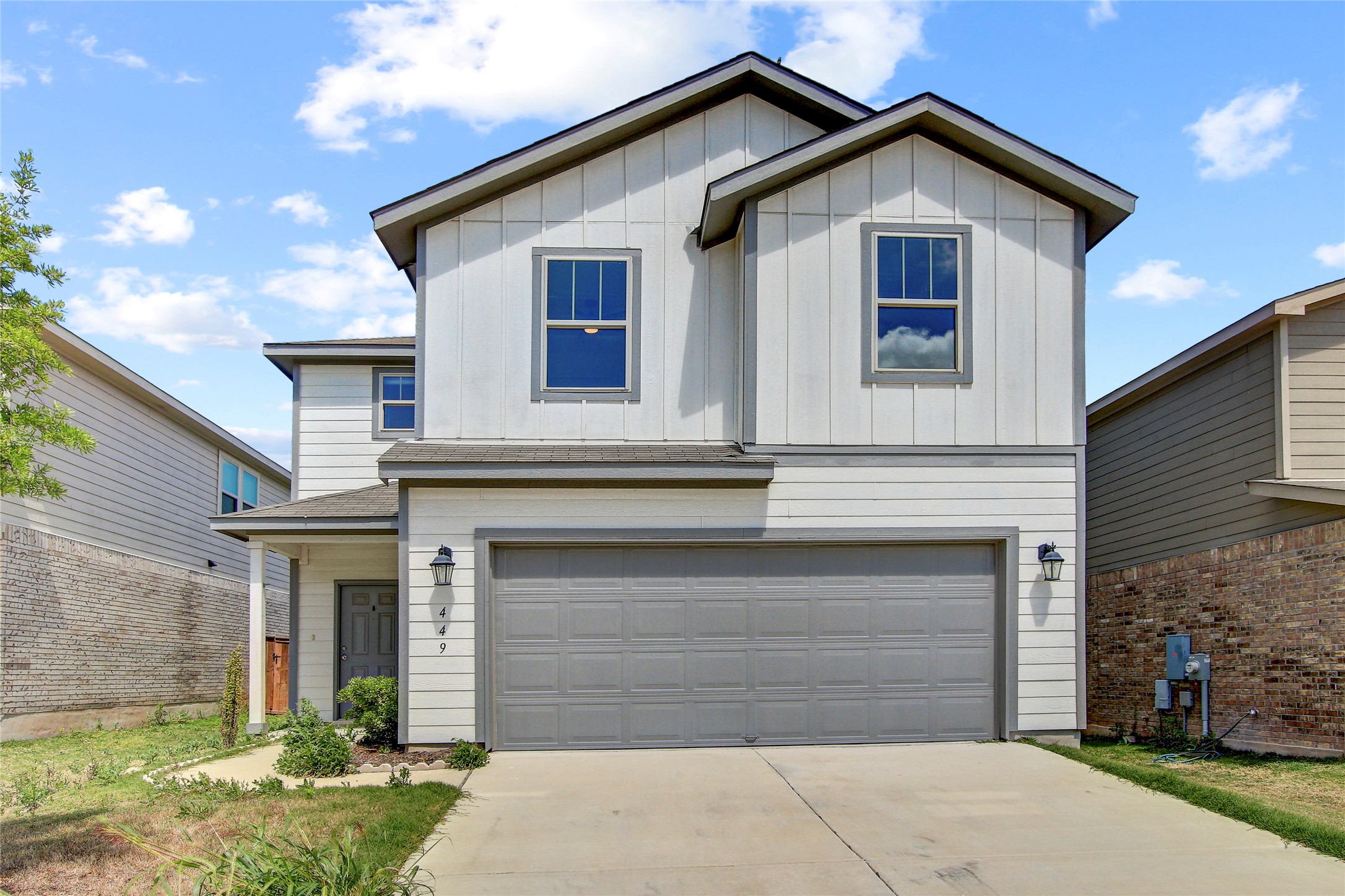 Two-story residence featuring a white and gray exterior, an attached two-car garage, and a covered entry