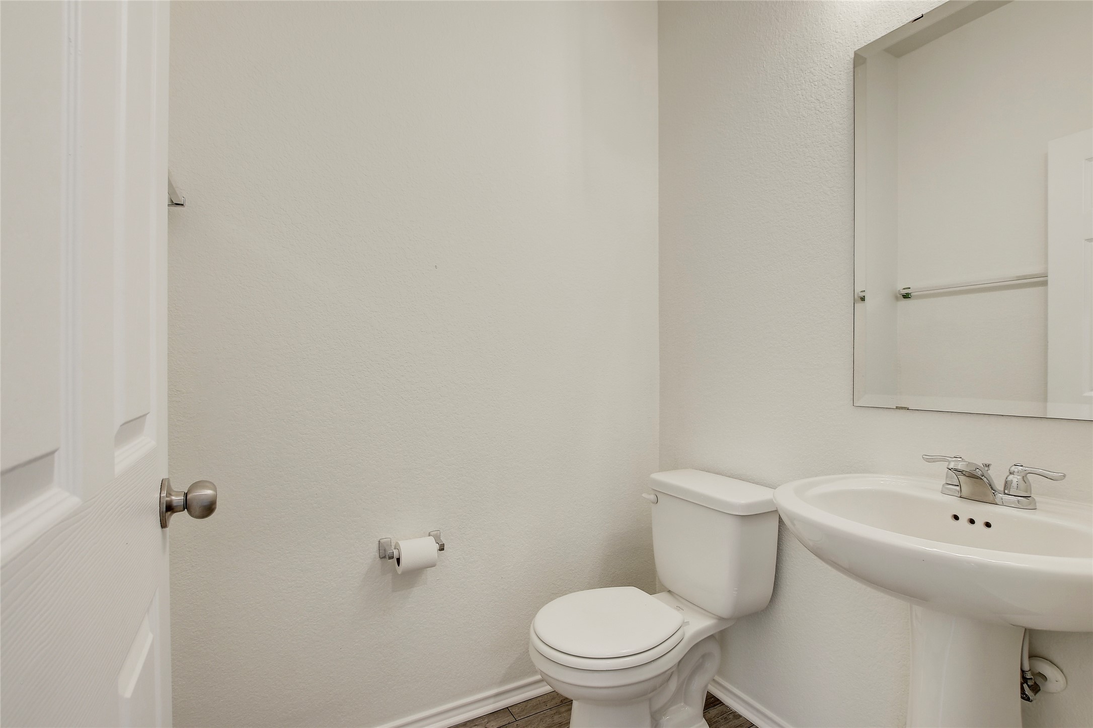 449 Stone Water Lane Jarrell, TX 76537 - Photo 2 of 18 Pedestal sink with chrome faucet, wall-mounted mirror, white toilet, and wood-finish flooring