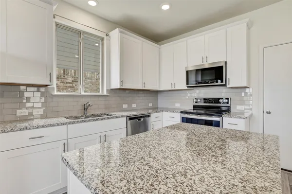 a kitchen with stainless steel appliances granite countertop a stove a sink and a microwave
