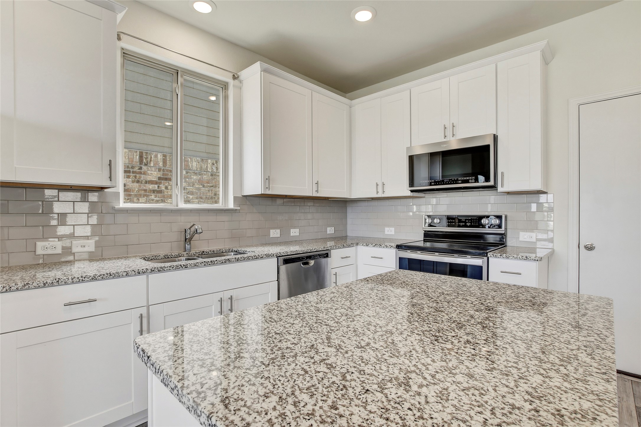 449 Stone Water Lane Jarrell, TX 76537 - Photo 4 of 18 Kitchen featuring white cabinetry, granite countertops, a stainless steel microwave, and a glass tile backsplash