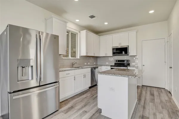 a kitchen with stainless steel appliances white cabinets and wooden floor