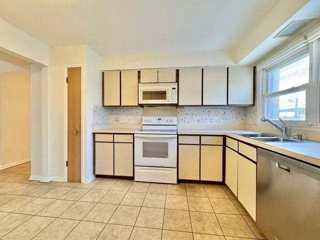 a large kitchen with stainless steel appliances granite countertop a stove a sink and a refrigerator