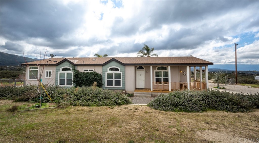 44260 Taffle Ranch Road Hemet, CA 92544 - Photo 1 of 1 a view of a white house next to a yard with plants and trees