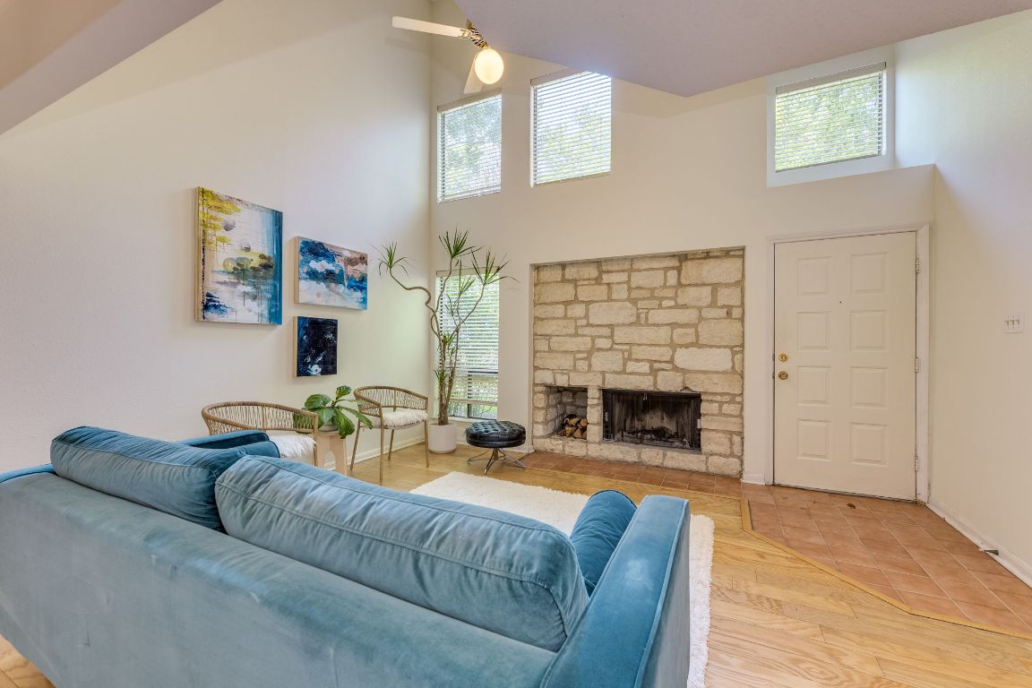 9226 Jollyville Road, Unit 132 Austin, TX 78759 - Photo 5 of 25 Living area featuring a towering ceiling, a fireplace, light wood-type flooring, and ceiling fan
