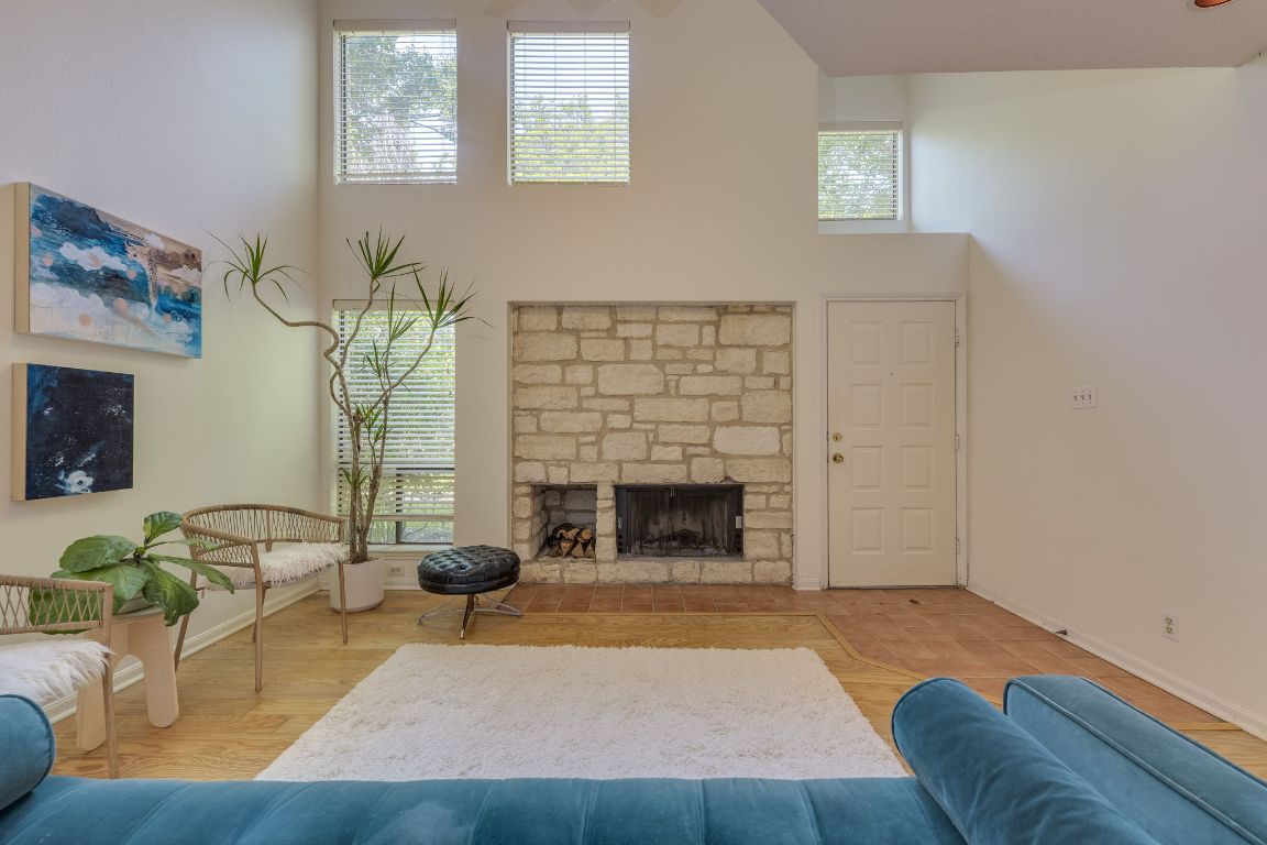 9226 Jollyville Road, Unit 132 Austin, TX 78759 - Photo 6 of 25 Living room featuring a towering ceiling, plenty of natural light, a fireplace, and wood finished floors