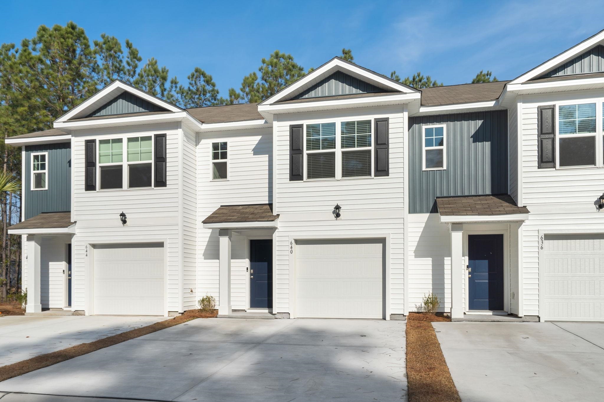 View of front of home featuring roof with shingles, board and batten siding, and driveway