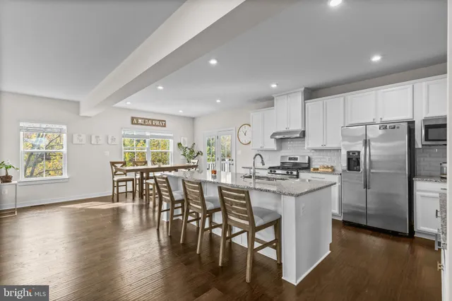 a kitchen with stainless steel appliances a dining table chairs stove and refrigerator
