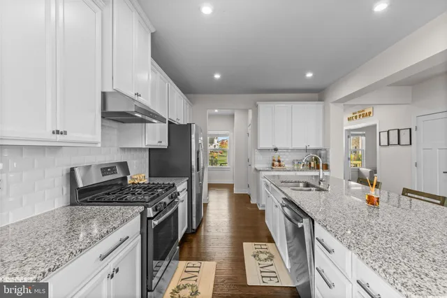 a large kitchen with stainless steel appliances granite countertop a lot of counter space and wooden floors