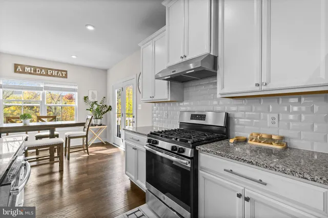 a kitchen with stainless steel appliances granite countertop a stove and white cabinets