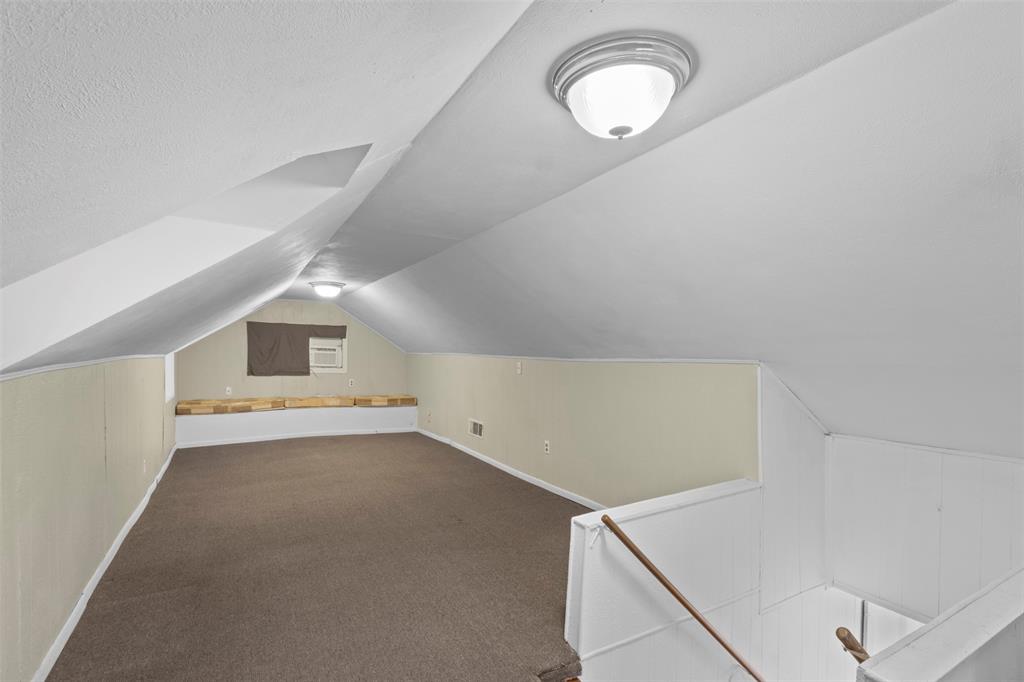 829 West 9th Street Bonham, TX 75418 - Photo 22 of 30 Finished attic space featuring brown carpeting, light beige wall panels, a built-in window air conditioning unit, and a built-in wood-finish bench