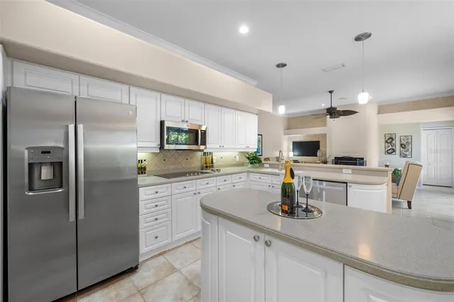 a kitchen with stainless steel appliances kitchen island granite countertop a refrigerator a stove a oven with white cabinets