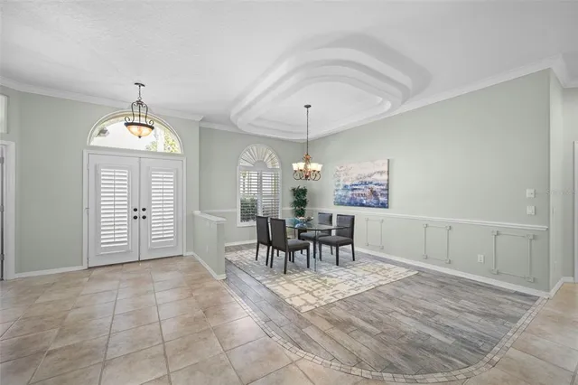 a dining room with chandelier and wooden floor
