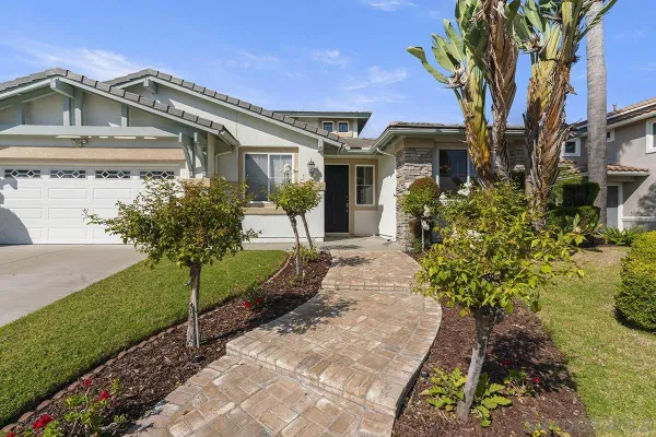a front view of a house with a yard and potted plants
